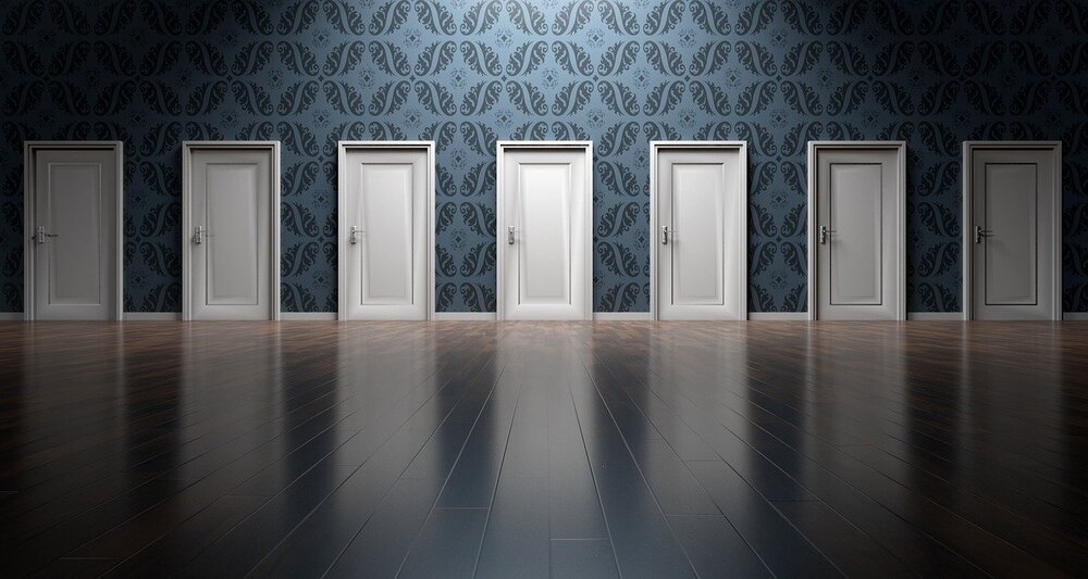 The meme is a picture of a room with five doors, each labeled with a different answer to the question "What do you call a group of cows playing instruments?" The answers are "A moo-sical band", "A herd of note", "A cow-abunga band", "A beefy orchestra", and "A udderly ridiculous band".